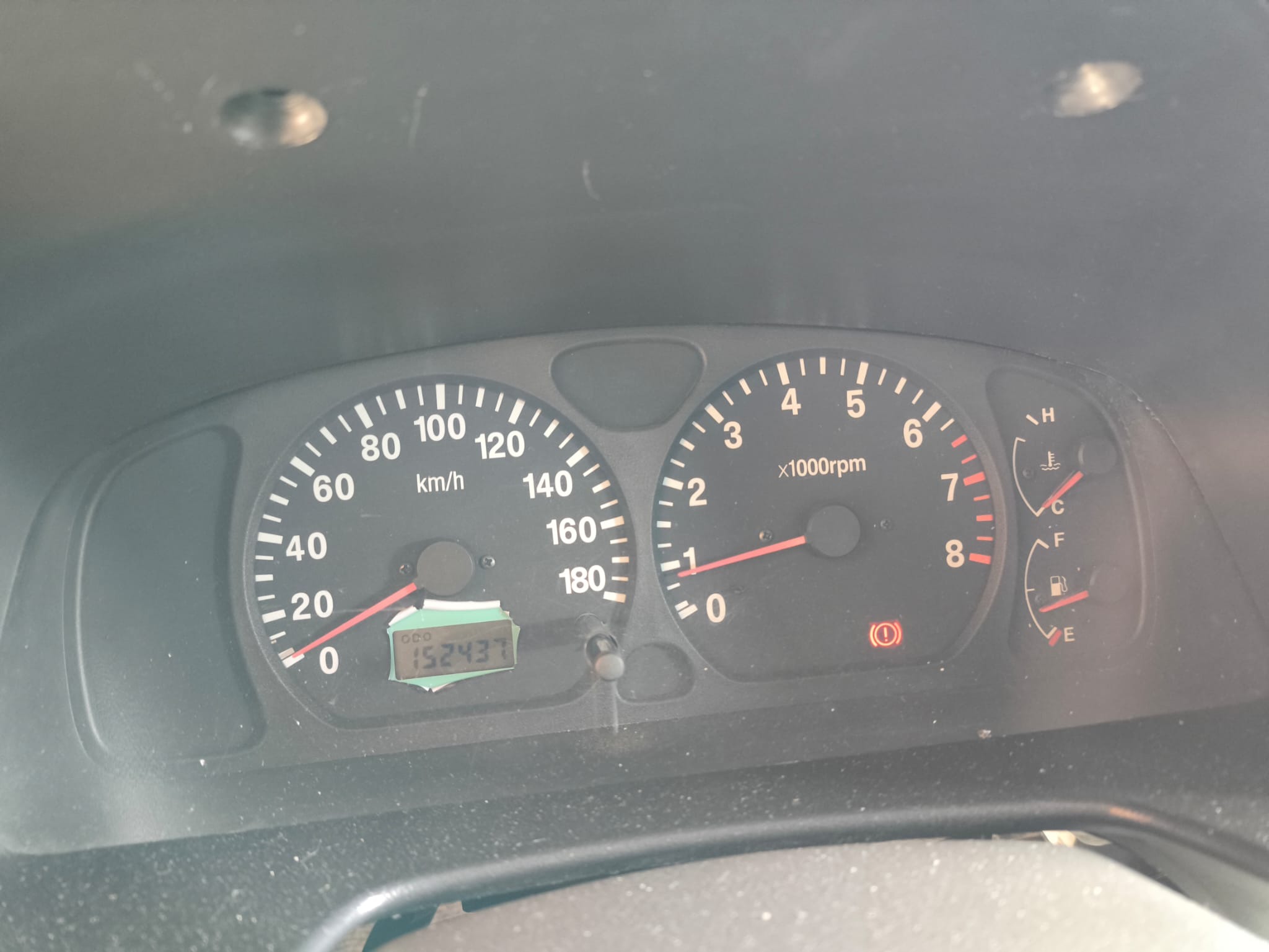 Cuadro de instrumentos mostrando 152.437 km, testigo encendido (freno de mano) y combustible en reserva