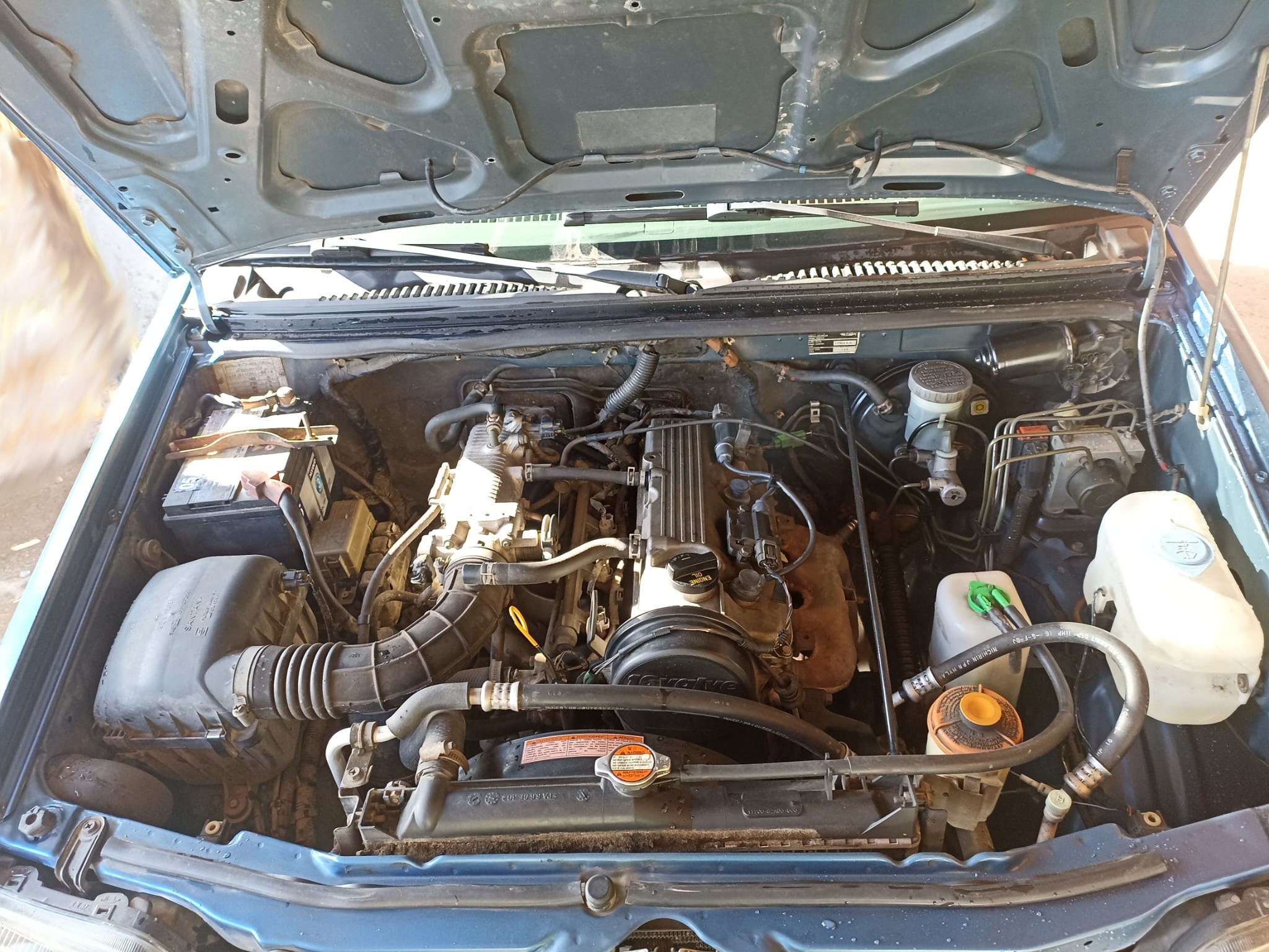 Compartimento motor con depósitos de líquidos visibles, suciedad notable